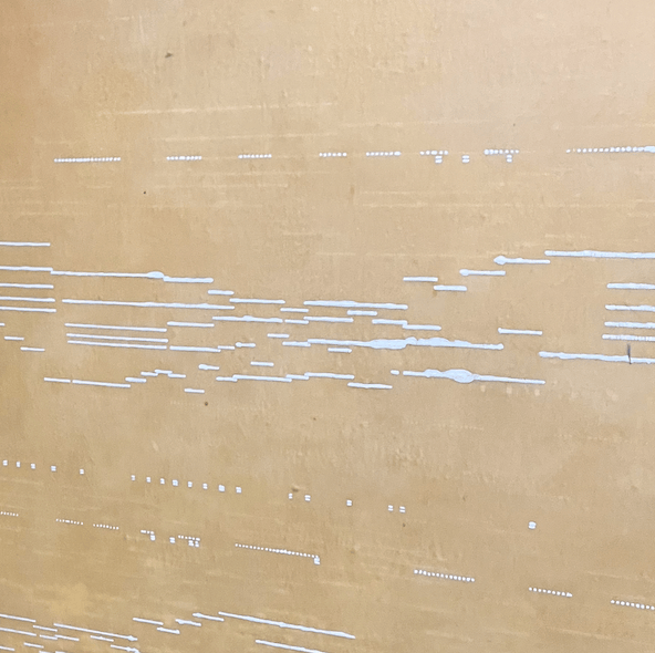 Close-up of a textured wall with varying white lines and dots on a beige background.